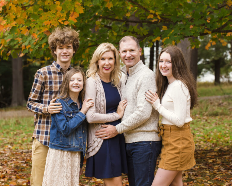 Family standing in fall leaves