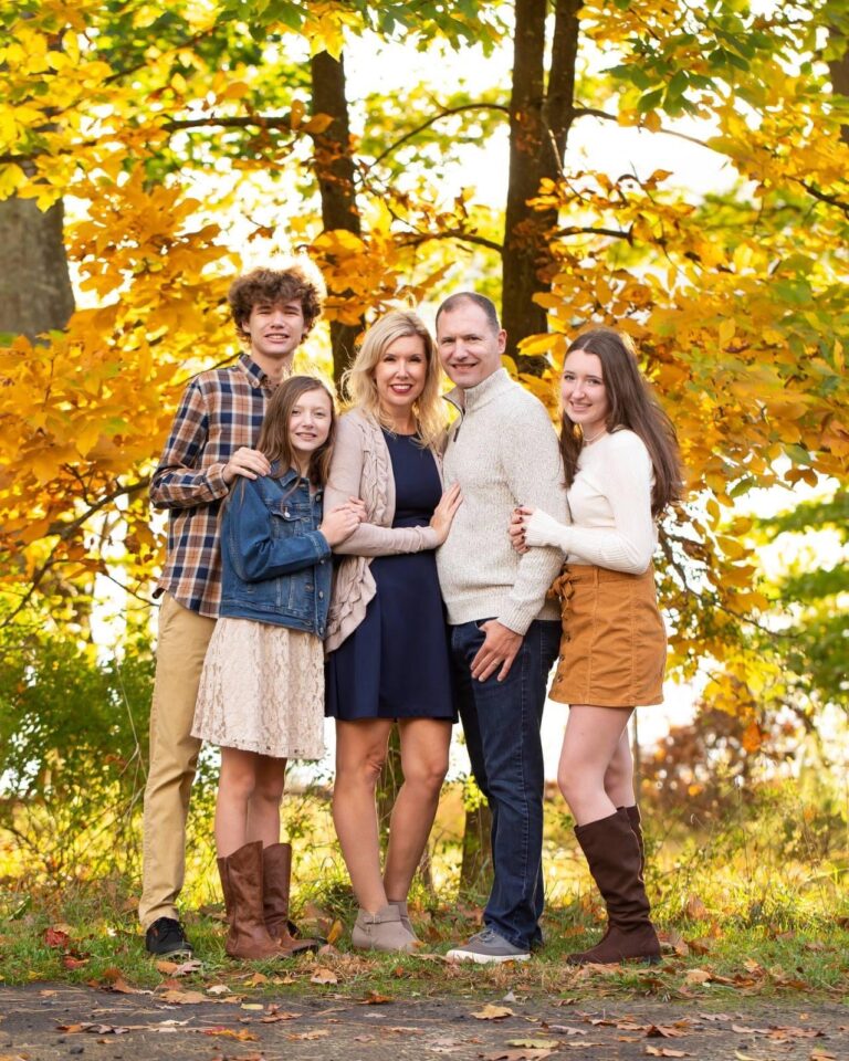 family standing in front of fall trees