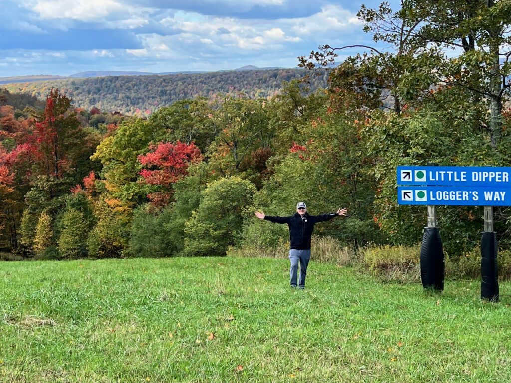 Man with fall trees standing on grass ski slope