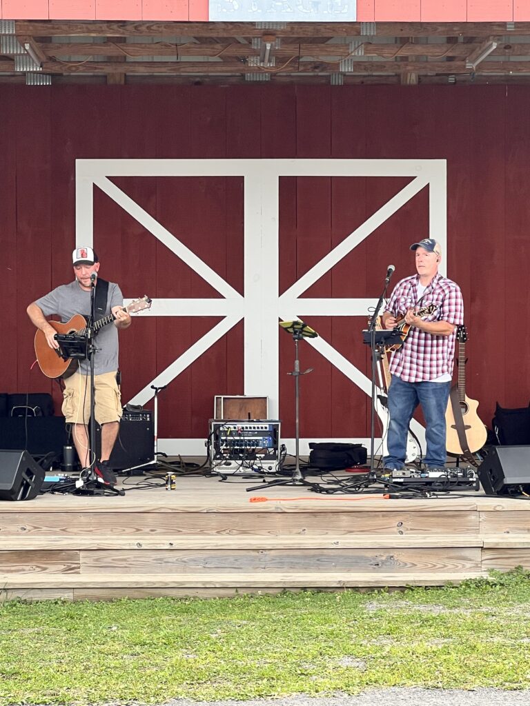 band playing music on a stage with red barn