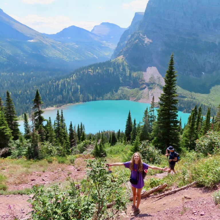 Hikers standing in front of neon blue Grinnell Lake