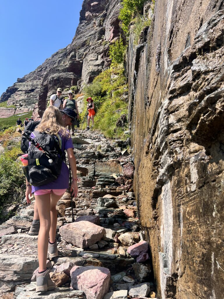 Hikers climbing up rocks on Grinnell Glacier Trail in Glacier National Park