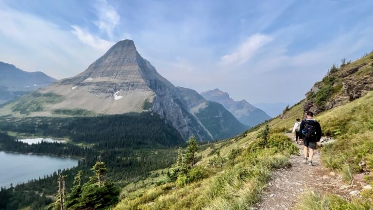 Hikers on a trail leading to a lake and mountains