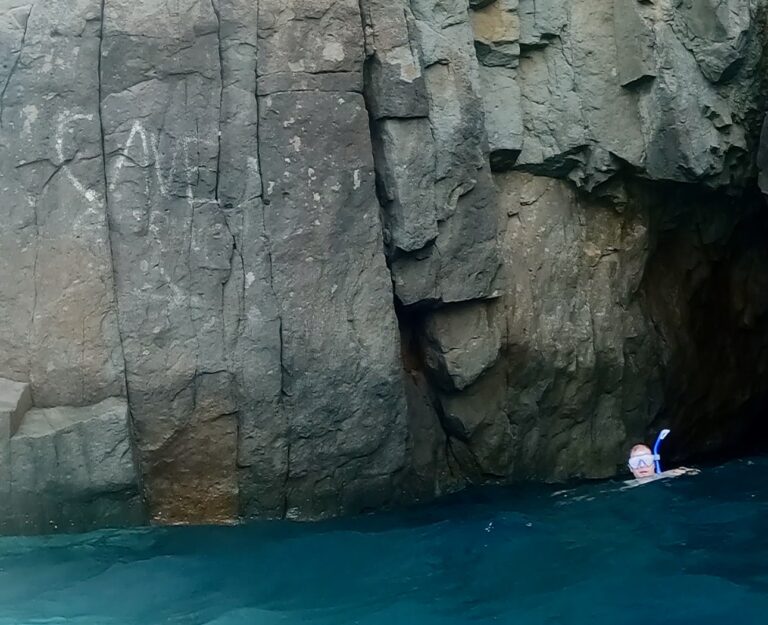 Snorkeling at a cave at the black beach in Santorini, Greece